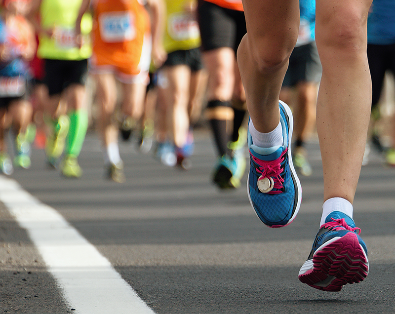 Nahaufnahme der Beine von Marathonläufern auf einem Wettkampf mit Laufsocken gegen Blasen von Wrightsock.